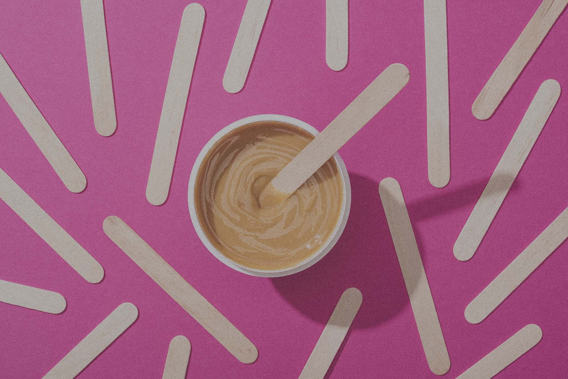 top view of depilation wax in container with sticks on pink back